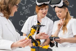 Shot of two students wearing virtual reality glasses and working in a classroom with their teacher