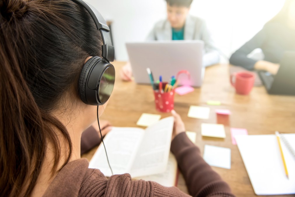 young woman reading wearing headphones in classroom