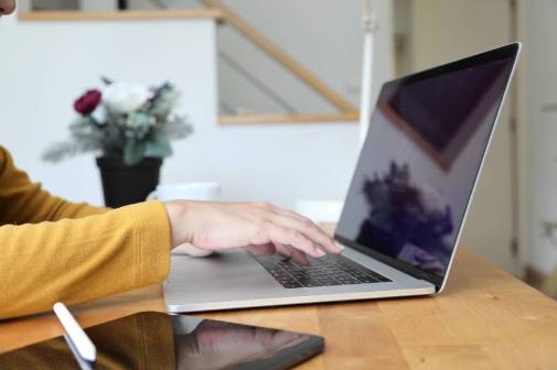 Photograph of a woman using her laptop - focused on her hands.